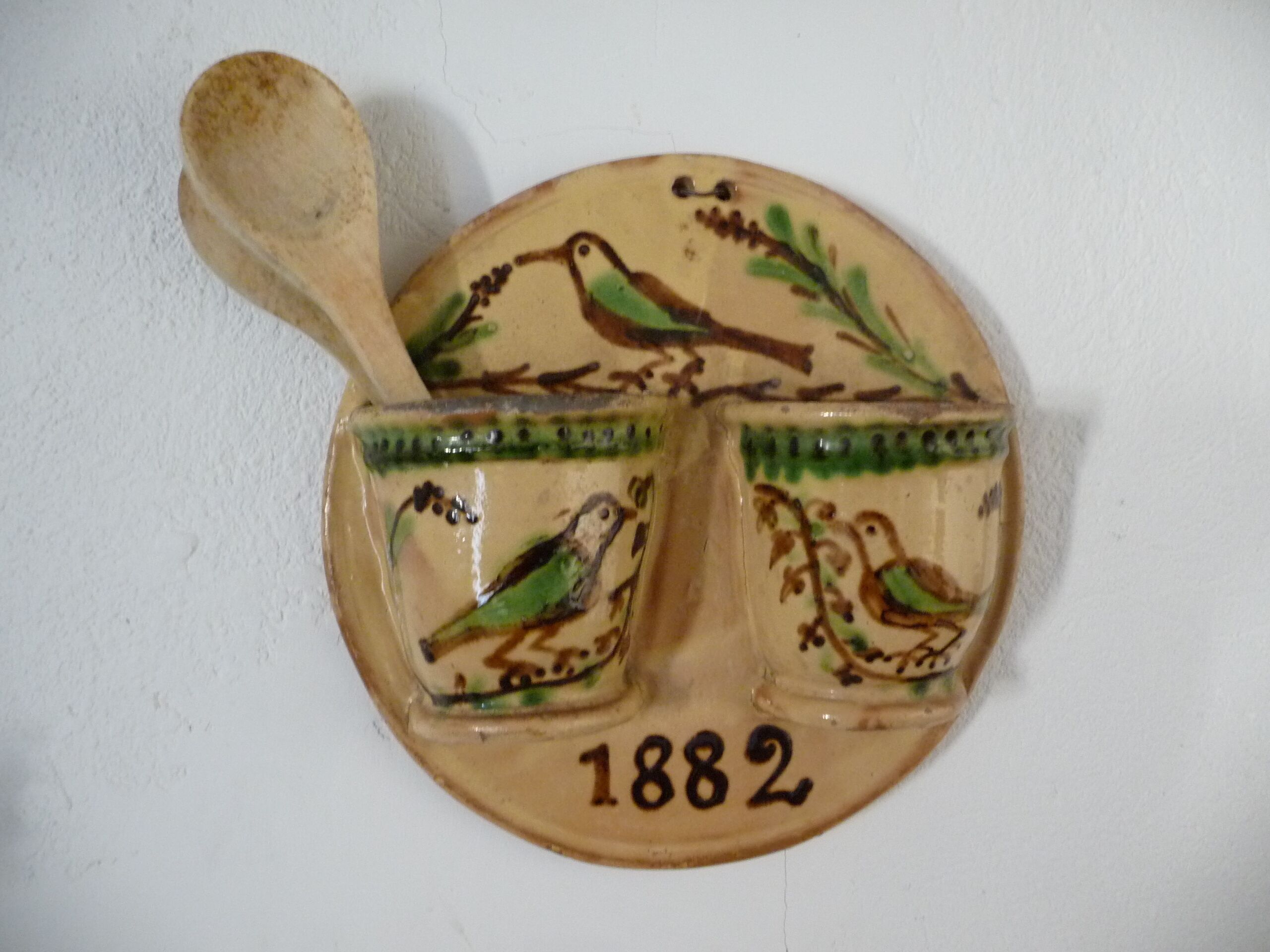 A ceramic wall piece with birds and the year 1882.