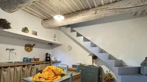 Une cuisine rustique comprenant une table à manger, des chaises, un escalier et un petit meuble.