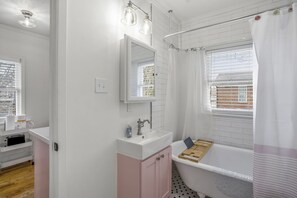 Een bad/douchecombinatie, een haardroger, handdoeken, zeep