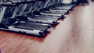 A row of treadmills in a gym with a wooden floor and a patterned wall.