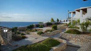 A coastal property with stone pathways, greenery, and a view of the sea. - Villa 78 m2 in Agia Irini, 350 Meter to the Beach for 4 Guests With Pool Access! (Paros)