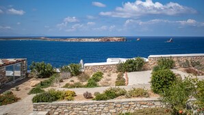 A coastal property with a stone wall, garden, and ocean view. - Villa 78 m2 in Agia Irini, 350 Meter to the Beach for 4 Guests With Pool Access! (Paros)