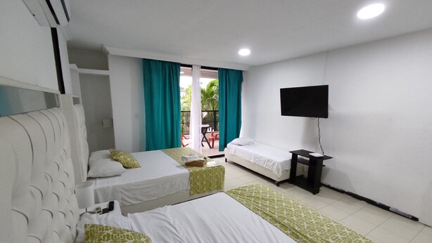 A hotel room with two beds, a TV, and a balcony with a table and chairs. - 2 Bedroom Apartment Near The Sea With Air Conditioning And Wifi (Cartagena)