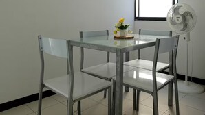 A dining area with a glass table and metal chairs, a small potted plant, and a standing fan. - 2 Bedroom Apartment Near The Sea With Air Conditioning And Wifi (Cartagena)