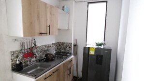 A compact kitchen with wooden cabinets, a stainless steel sink, and a black refrigerator. - 2 Bedroom Apartment Near The Sea With Air Conditioning And Wifi (Cartagena)