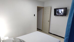 A bedroom with a bed, pillows, a television on the wall, and a door. - 2 Bedroom Apartment Near The Sea With Air Conditioning And Wifi (Cartagena)