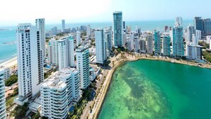 A coastal cityscape with high-rise buildings, a beach, and a clear view of the ocean.