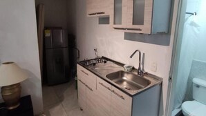 A compact kitchen with a built-in stove, a sink, and cabinets.