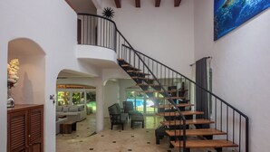Un salón espacioso con una escalera de madera, un ventanal y vistas al exterior.