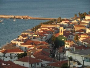 Uma vila costeira com edifícios, uma igreja e barcos na água.