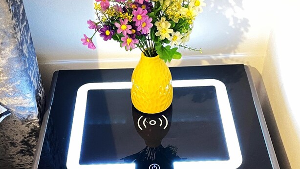 En skrivare med en gul vas med blommor ovanpå.