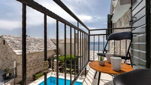 A balcony with a pool, a table with chairs, and a view of the sea. - Villa Topolinath Pool (Baska Voda)