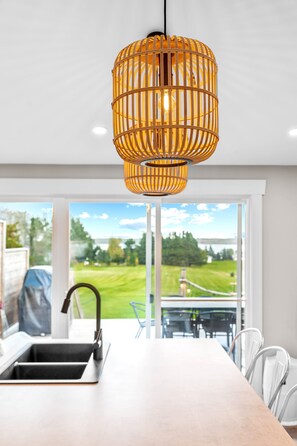 Una cocina moderna con un amplio ventanal, un colgador de luz y vistas a un paisaje verde.