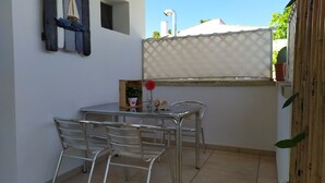 A small outdoor patio with a table and chairs, a potted plant, and a decorative sail. - lu Ientu House in Otranto, Baia dei Turchi Area No001 (Otranto)