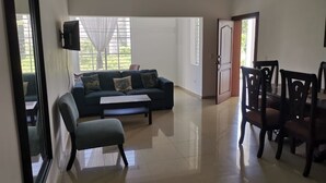 A spacious living room with a sofa, a coffee table, and a dining area with chairs.