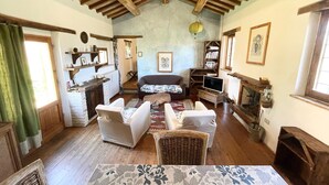 A cozy living room with a fireplace, wooden ceiling beams, a sofa, and a television. - Spoleto Tranquilita Sleeps 20 With Wifi Pool Yoga Studio Gardens and Views (Spoleto)