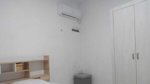 A bedroom with a bed, a wardrobe, a small stool, and a trash bin. - Modern Apartment With Common Pool Near Sandy Beach (Pointe Aux Piments)