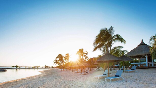 A beach with sun loungers and thatched-roof structures. - Modern Apartment With Common Pool Near Sandy Beach (Pointe Aux Piments)