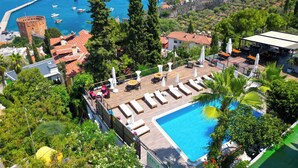 A resort with a pool, lounge chairs, and a view of the sea and a historic tower. - Castle Boutique Hotel Alanya (Alanya)