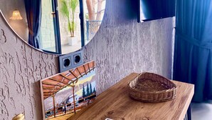 A room with a large mirror, a painting, a wooden table, and a wicker basket. - Castle Boutique Hotel Alanya (Alanya)