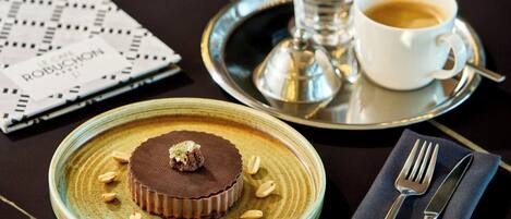 A dessert plate with a chocolate tart, a cup of coffee, and a menu on a table.