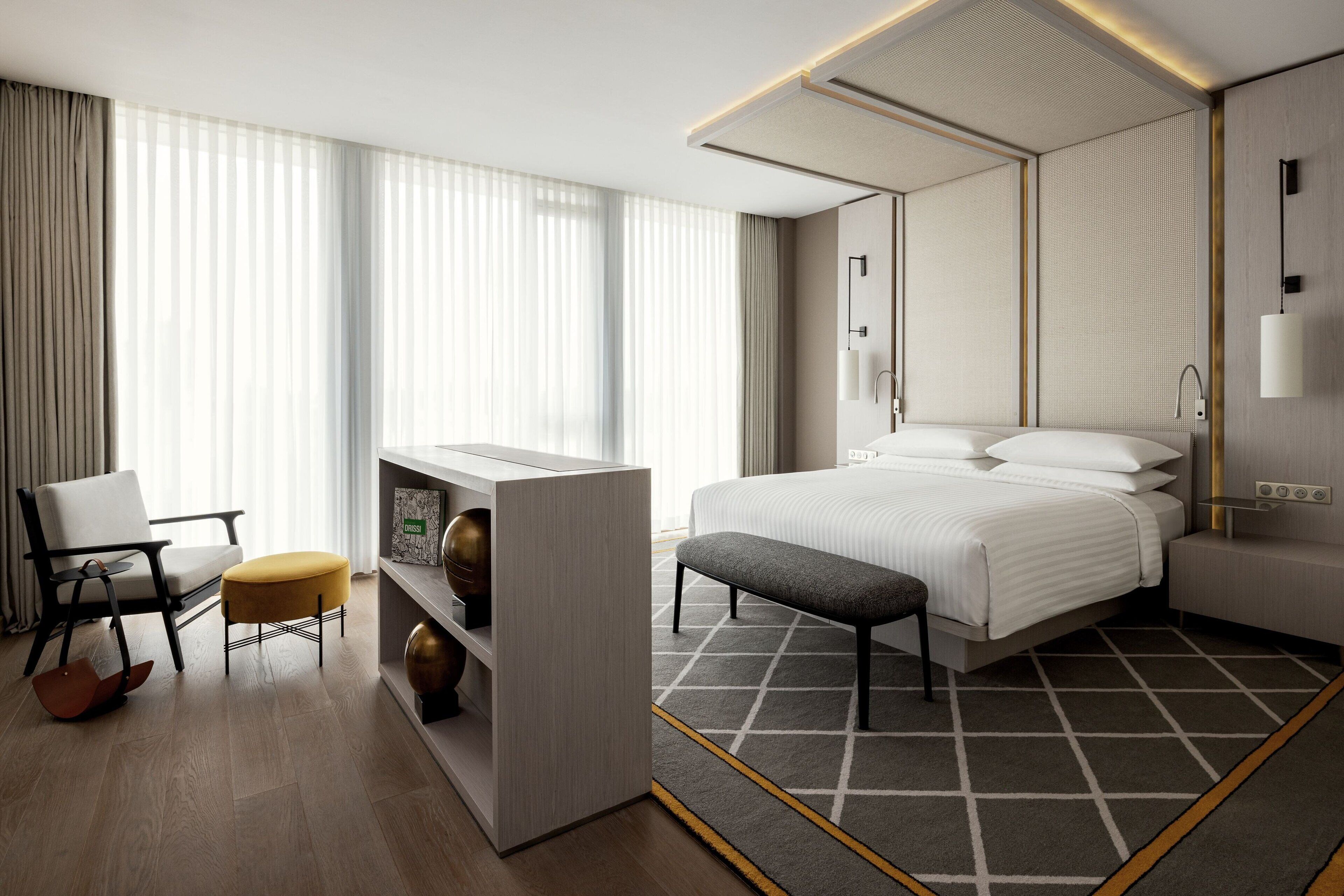 Una habitación de hotel moderna con una cama grande, un escritorio, una silla y un banco.