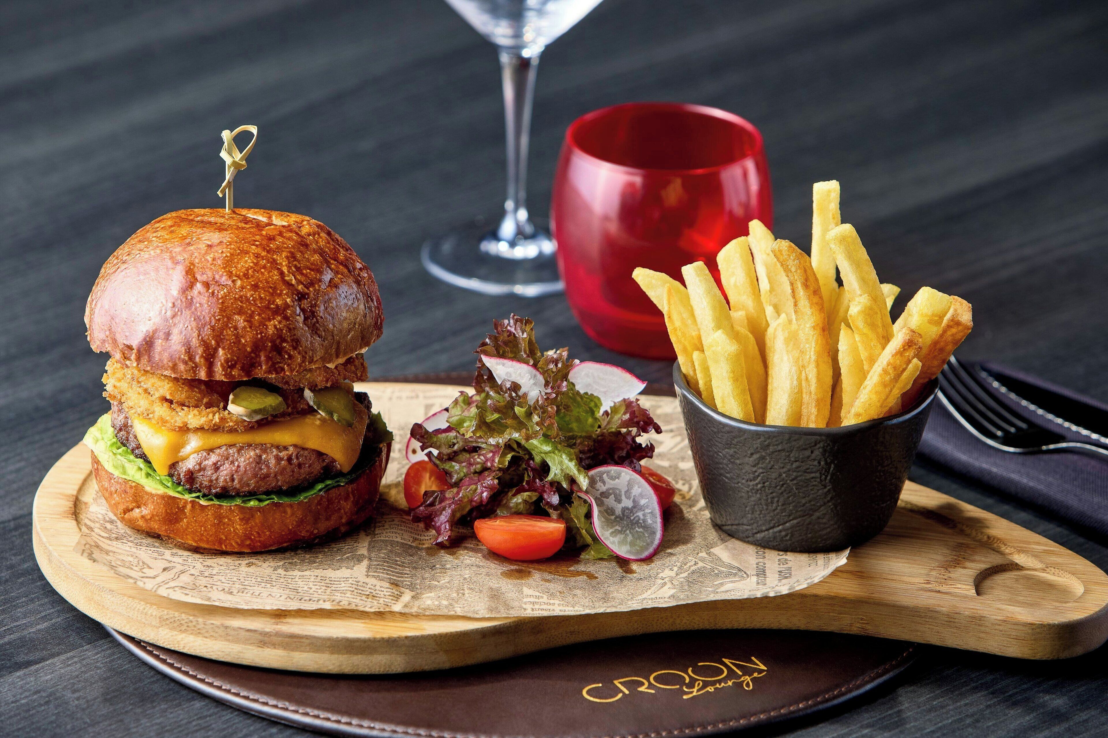 A burger with fries and a salad on a wooden board.