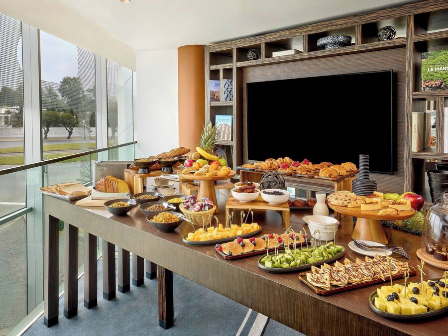 Una mesa de buffet con diferentes alimentos y un televisor al fondo.