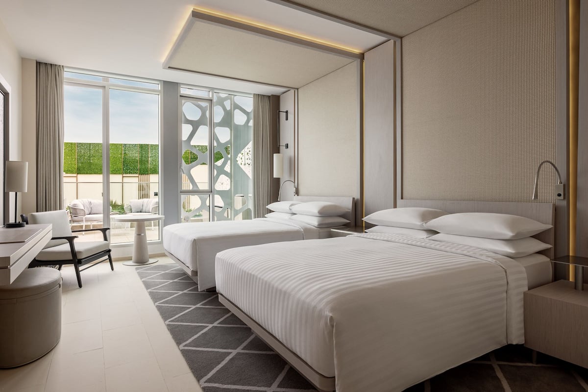 A modern hotel room with a large bed, a desk, and a view of the outdoors.