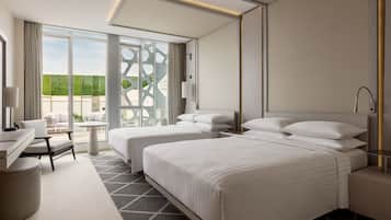 A modern hotel room with a large bed, a desk, and a view of the outdoors.