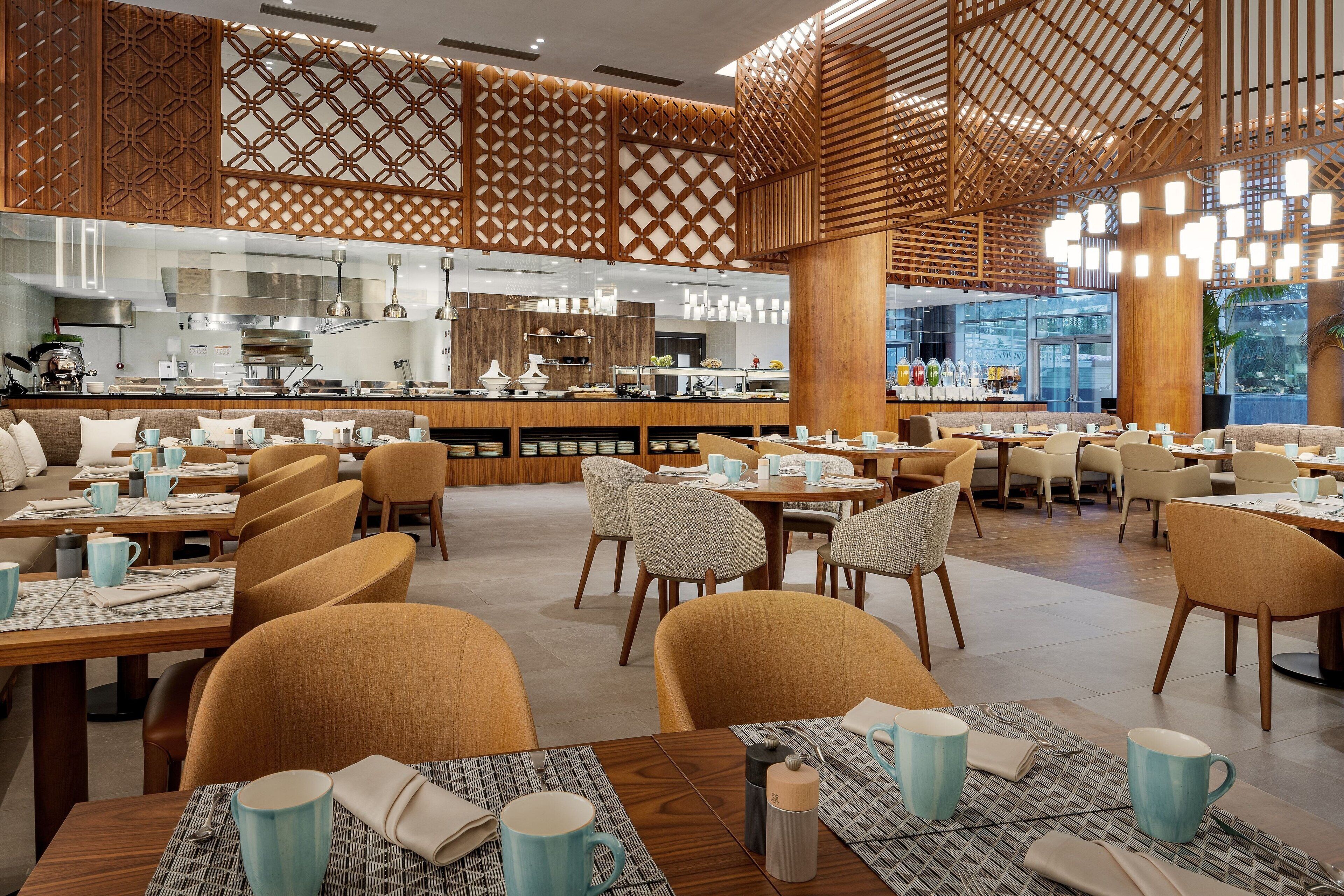 En rymlig restaurang med flera matplatser, en central bar och en modern inredning.