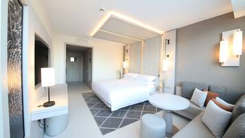 Une chambre d’hôtel moderne avec un lit, un canapé, une petite table et un miroir.