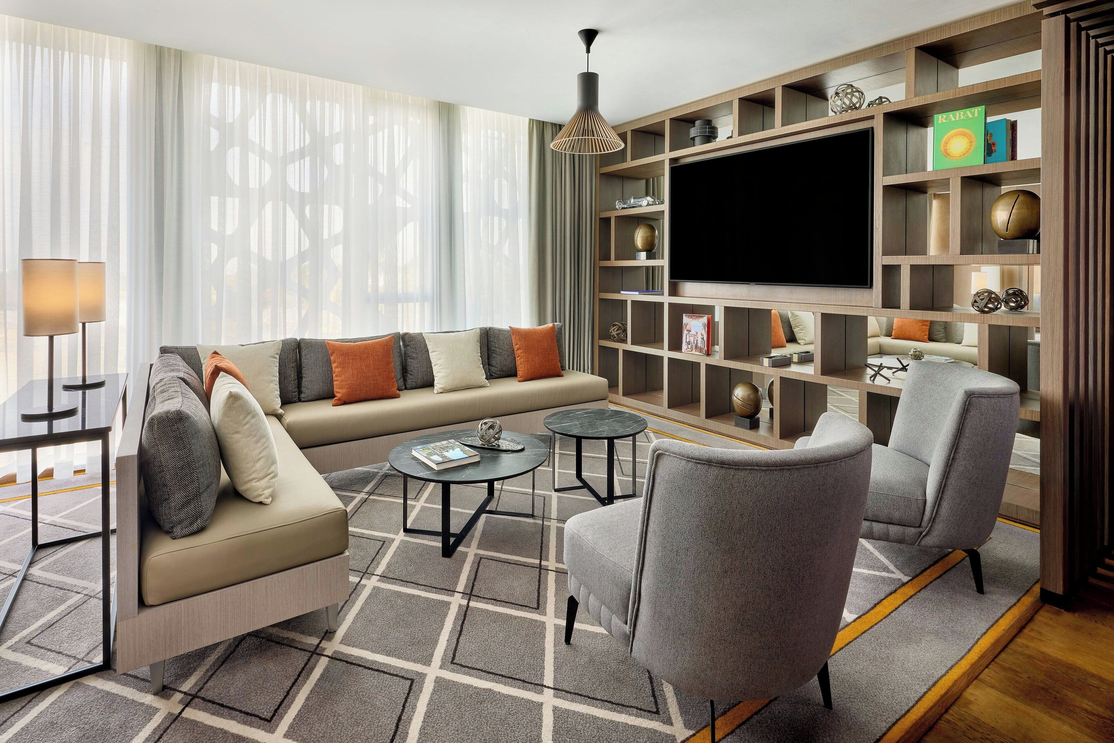 Una sala de estar moderna con un sofá, dos sillones, una mesa de centro y un televisor.