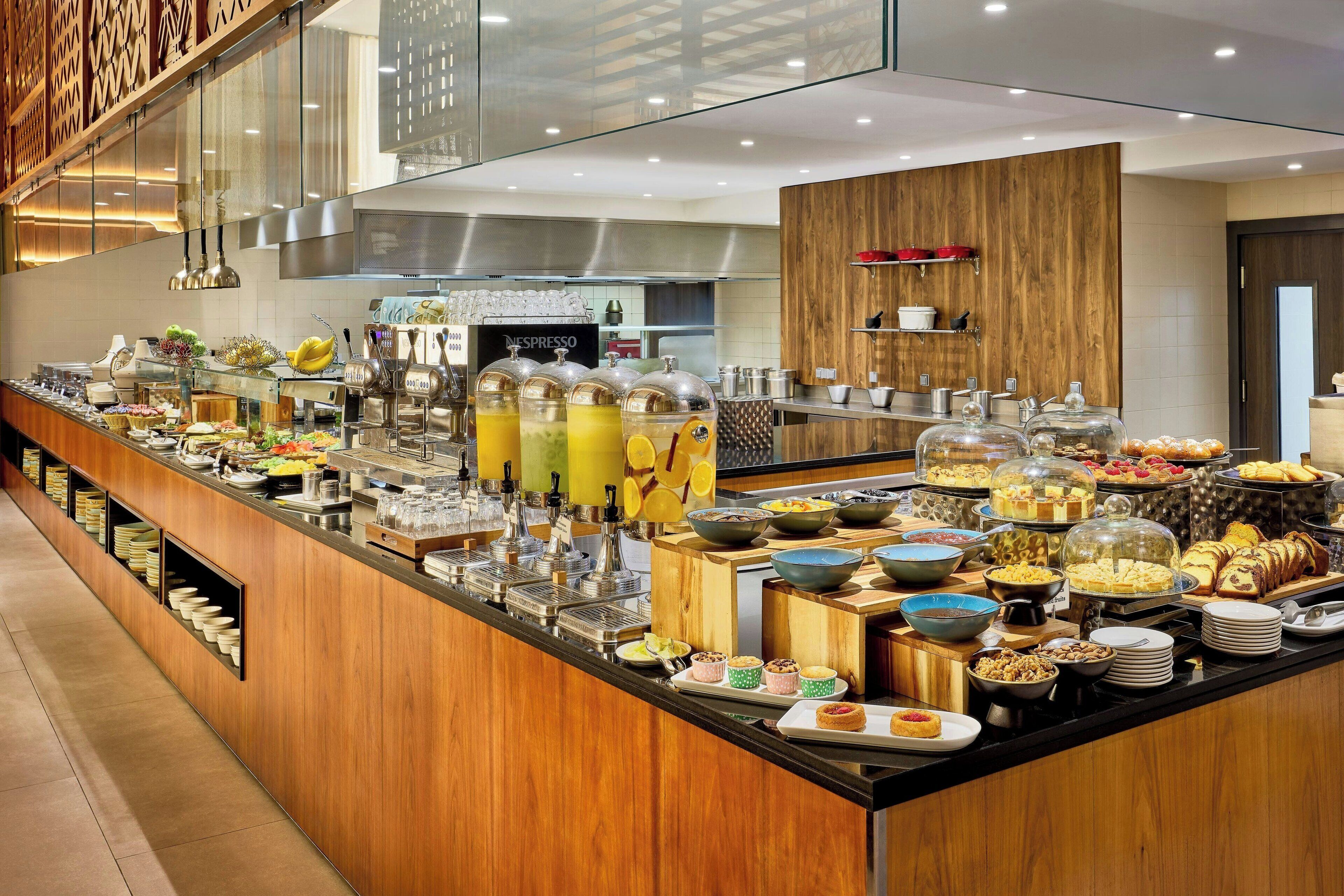 Un buffet proposant une variété de plats et de boissons, notamment des fruits, des pâtisseries et un coin café.