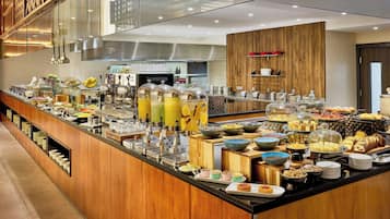 Un buffet proposant une variété de plats et de boissons, notamment des fruits, des pâtisseries et un coin café.