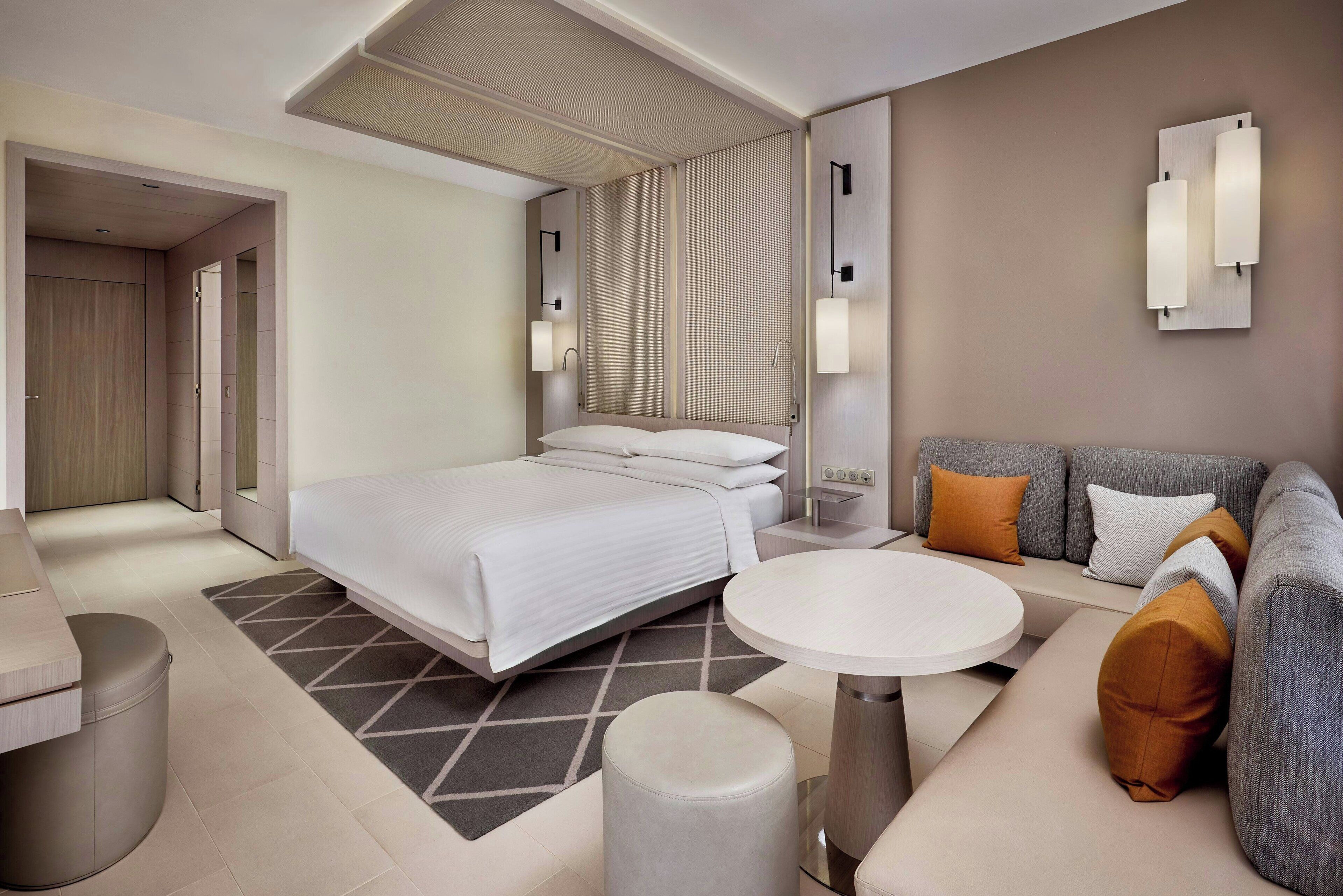 Een moderne hotelkamer met een groot bed, een bank, een ronde tafel en een klein krukje.