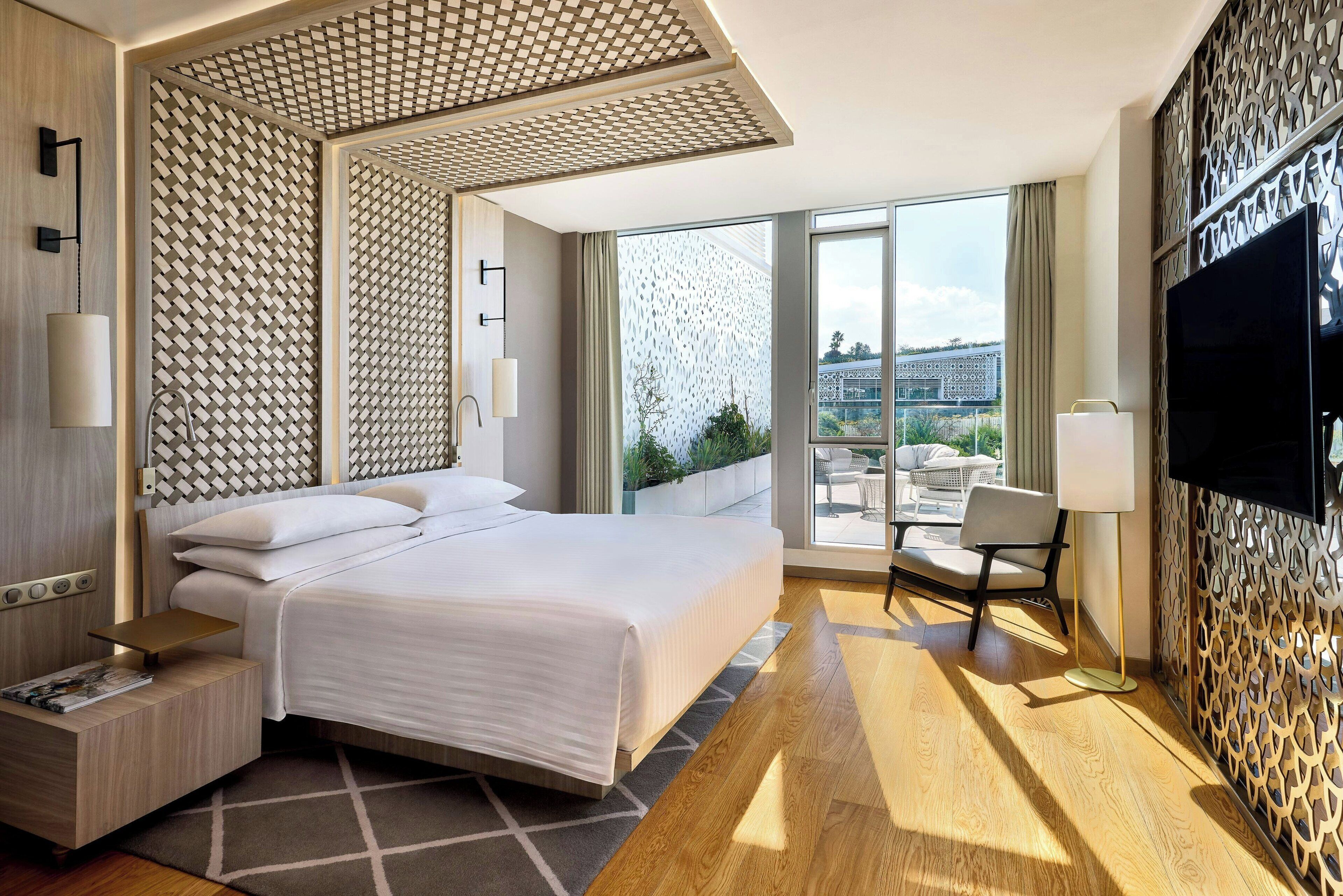 Une chambre d’hôtel moderne dotée d’un grand lit, d’une télévision, d’un bureau et d’un balcon avec vue.
