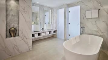 Une salle de bain moderne avec une baignoire sur pieds, des murs en marbre et un meuble-lavabo doté de plusieurs vasques.