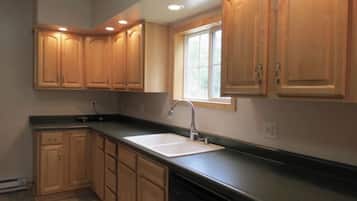 A kitchen with wooden cabinets, a window, and a sink.