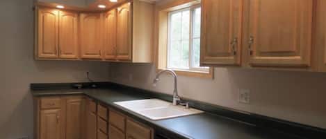 A kitchen with wooden cabinets, a window, and a sink.