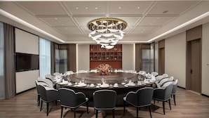 A conference room with a round table, chairs, a chandelier, and a decorative centerpiece.