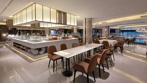 A modern dining area with a central island, multiple seating arrangements, and a view of the cityscape through large windows.