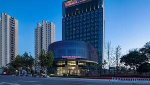 A modern hotel with a curved facade, large windows, and a prominent sign reading "RAMADA".