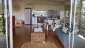 Cocina moderna con armarios blancos, refrigerador de acero inoxidable y comedor con mesa y sillas.