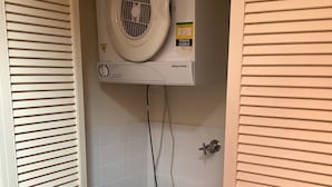 Pequeña lavandería con lavadora de carga frontal y ventilador de techo.