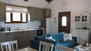Een moderne keuken met grijze kastjes, een wit aanrecht en een zithoek met een blauwe bank en witte stoelen.