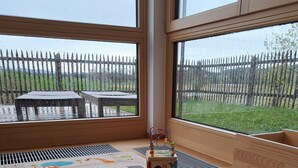 A room with a large window, a wooden playpen, and a colorful play mat with animal and vehicle designs. - Vacation apartment on the Haldershof ground floor (Wangen im Allgäu)