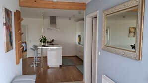 A modern kitchen with white cabinets, a stainless steel range hood, and a bar stool. - Vacation apartment on the Haldershof ground floor (Wangen im Allgäu)