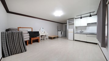 A compact living space with a kitchenette, a television, a desk, and a bed.