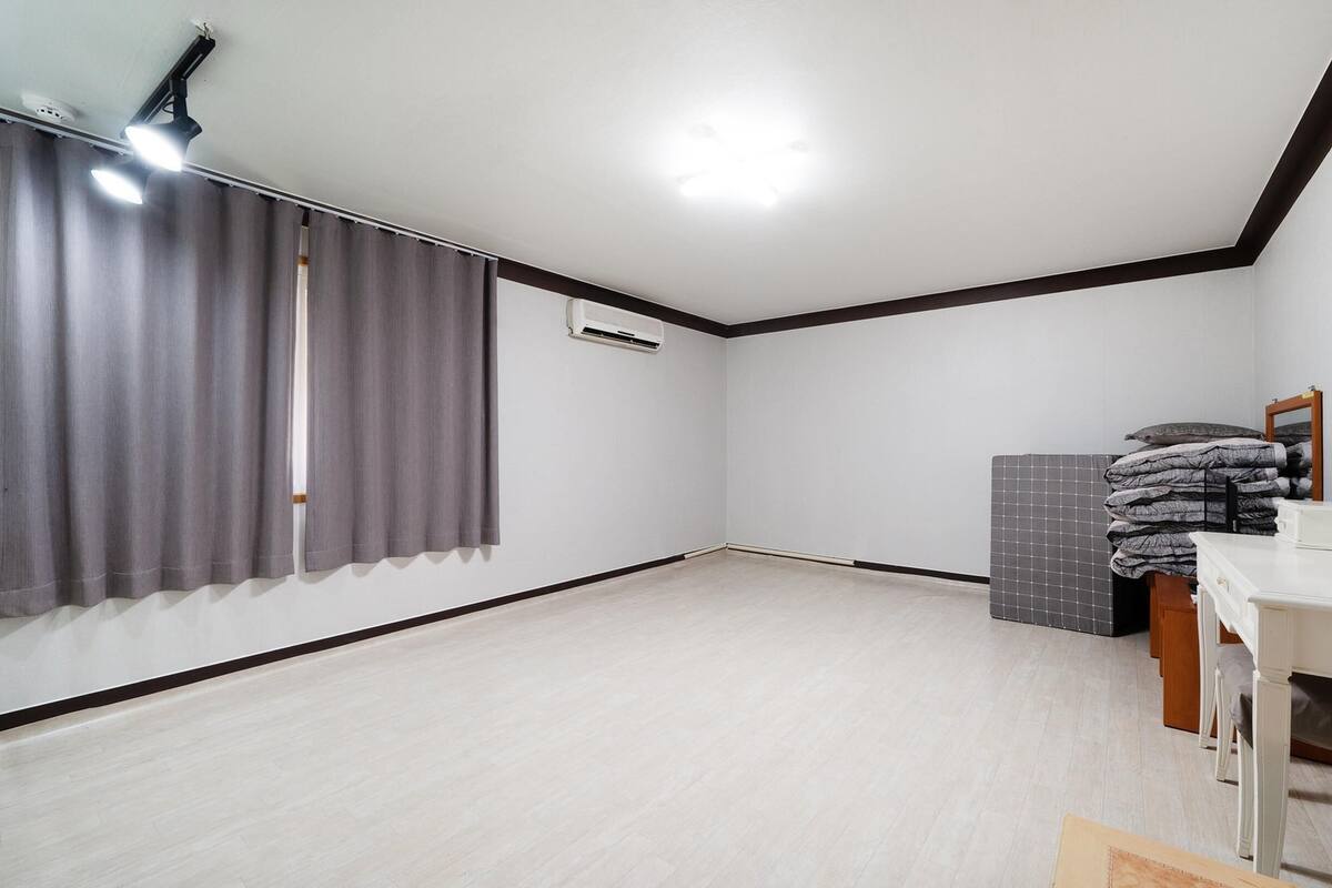 Ein Schlafzimmer mit einem Bett, einem Schminktisch, einem Spiegel und einem Fenster mit Vorhängen.